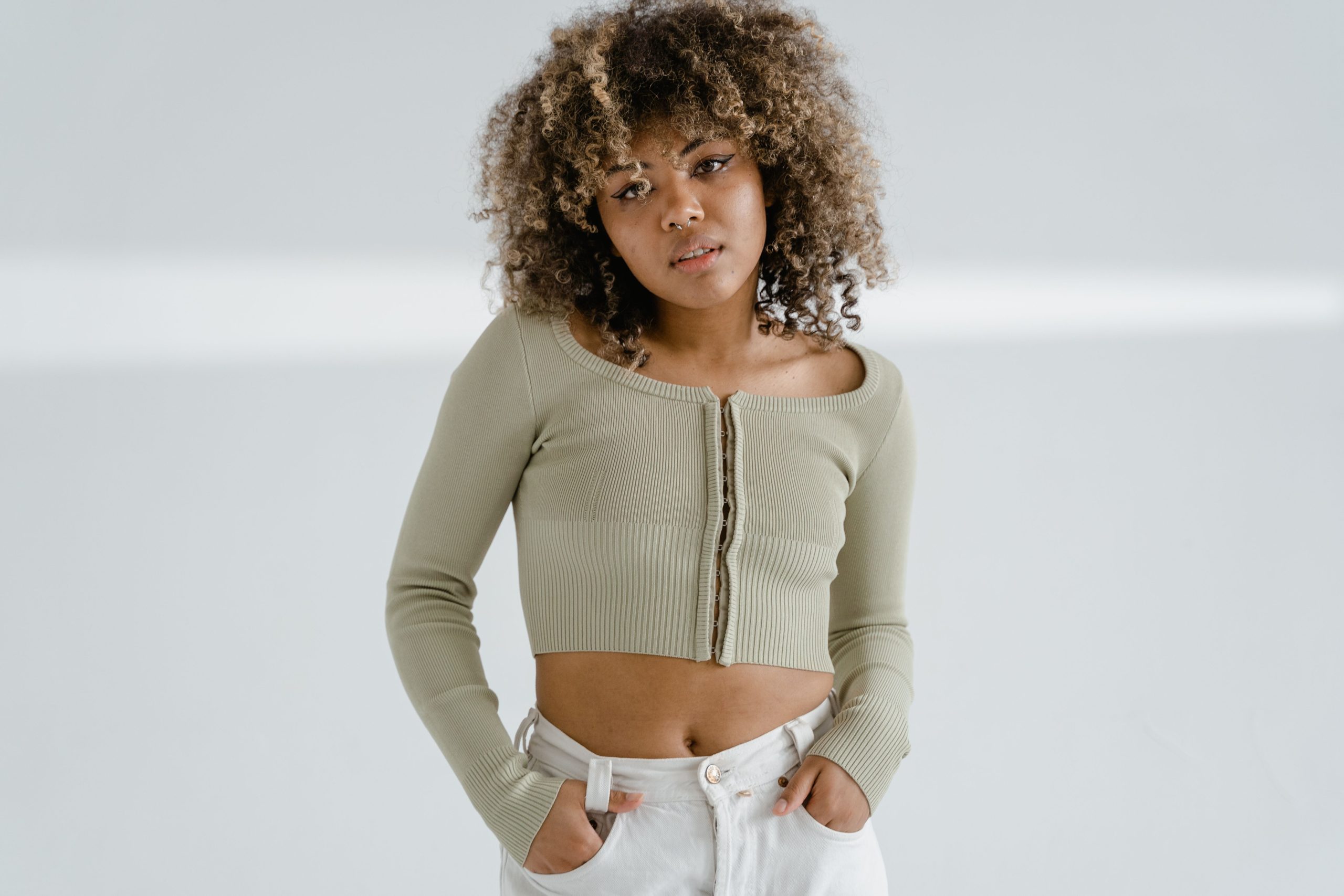 Femme élégante en crop top pose mur blanc