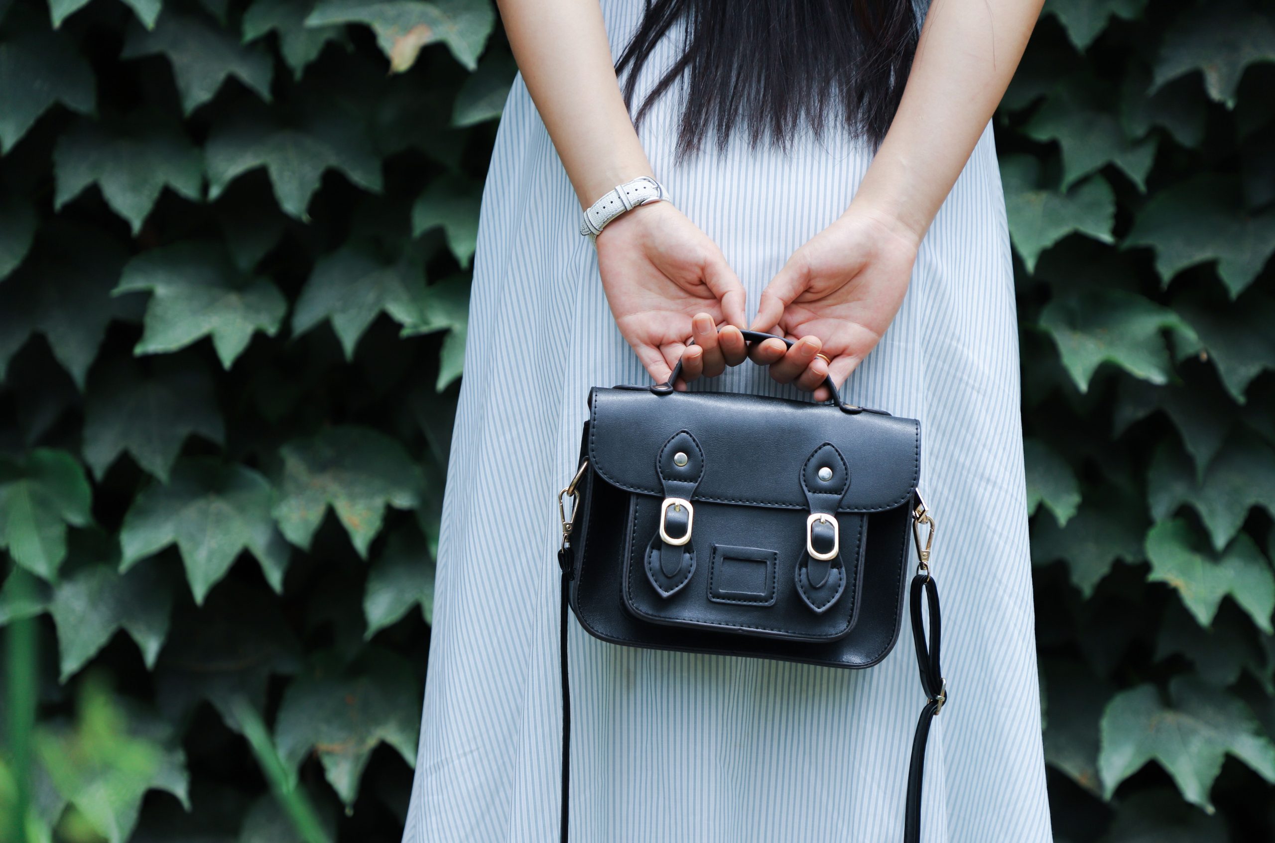 Femme tenant un sac à main noir en cuir