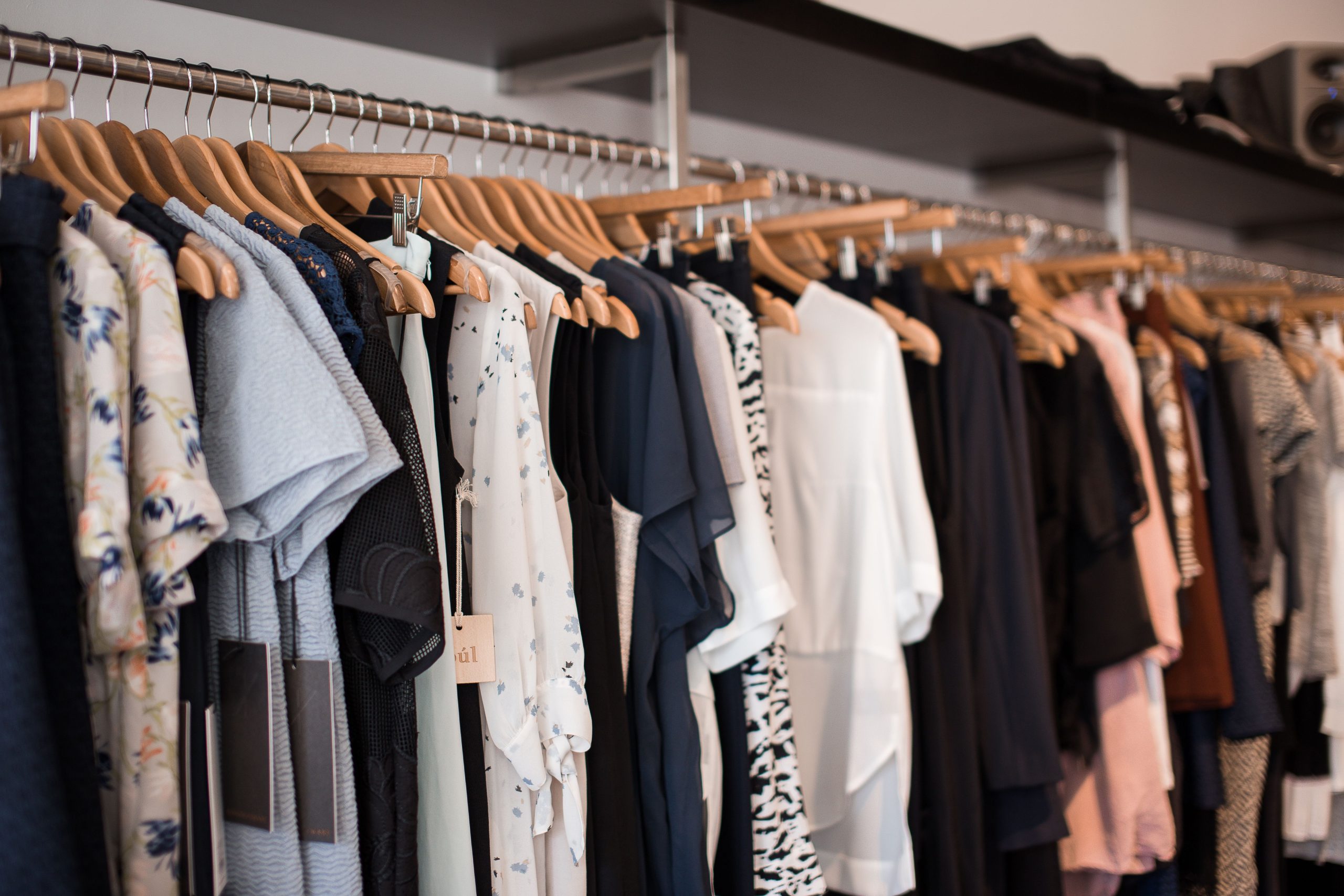 Vêtements colorés sur cintres bois en boutique.