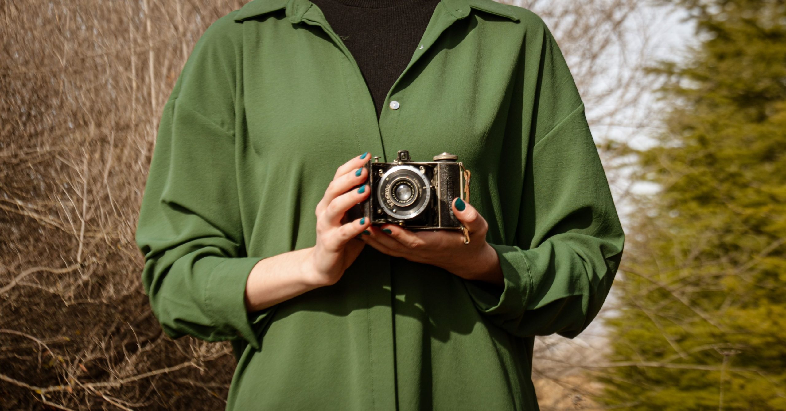 Femme en chemise verte avec appareil photo vintage